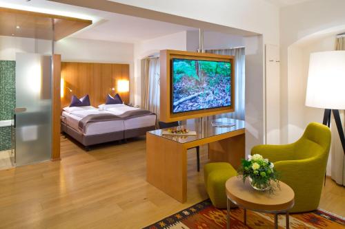 pokój hotelowy z łóżkiem i telewizorem w obiekcie Hotel Maximilian - Stadthaus Penz w mieście Innsbruck