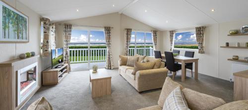 a living room with a couch and a table and a television at Clearwater lodge in Perranporth