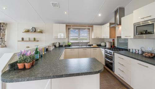 a kitchen with white cabinets and a black counter top at Clearwater lodge in Perranporth