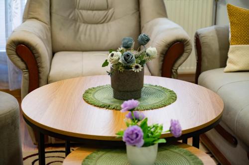 a coffee table with a vase of flowers on it at GRADINA - Stan na dan in Doboj