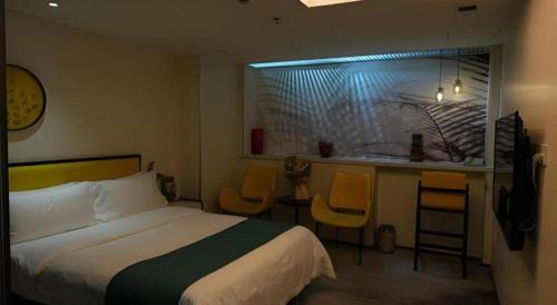 a bedroom with a bed and a kitchen with yellow chairs at Golden Central Hotel Shenzhen in Shenzhen