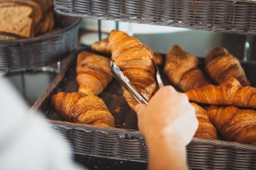 a person holding a tray of croissants and bread at C-Hotels Andromeda in Ostend