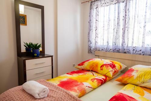 a bedroom with two beds with colorful pillows and a mirror at Gradina Stan na Dan in Doboj
