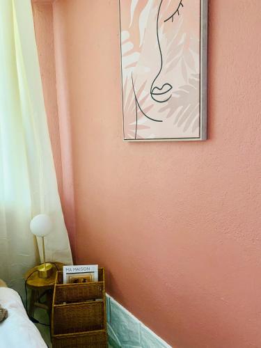 a bedroom with a pink wall with a picture on the wall at Les jardins de Phidji in Buzet-sur-Tarn