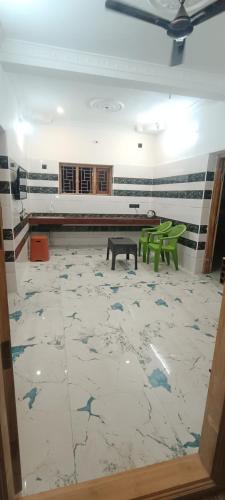 a room with a table and two green benches at Vhomes in Kuttālam