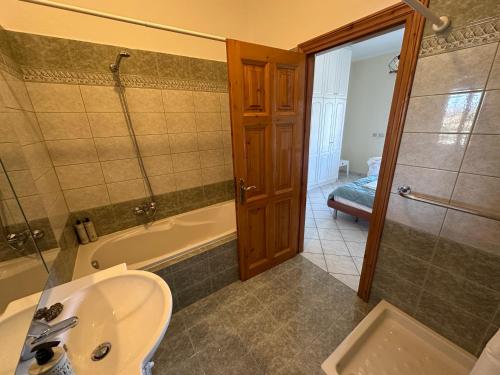 un bagno con lavandino, vasca e doccia di Sunsets and large pool in comfy Villa Avra Arillas a Arillas