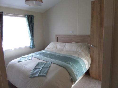 a bedroom with a bed with a blue blanket on it at Clearwater lodge in Perranporth