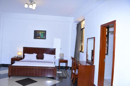 a bedroom with a bed and a desk and a mirror at Sun View Hotel in Addis Ababa