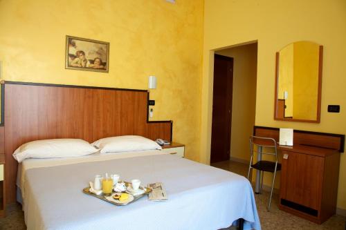 Una habitación de hotel con una cama con una bandeja de comida. en Hotel Sirena en Pineto