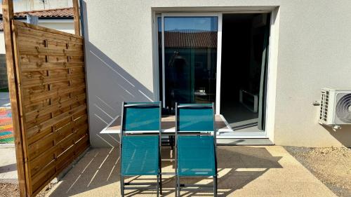 two blue chairs sitting on a table in front of a house at Lits faits, valise à poser, 3 mn Futuroscope in Chasseneuil-du-Poitou