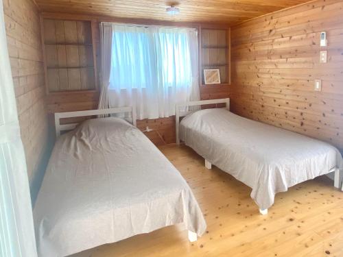 a room with two beds in a wooden cabin at Casa3 in Nakijin