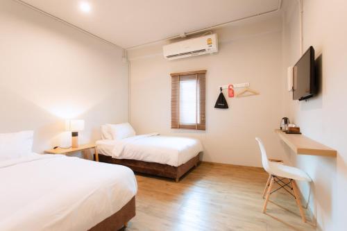 a room with two beds and a desk and a tv at Hotel PAPA Bangkok in Bangkok