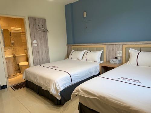 two beds in a hotel room with a bathroom at 鉑玥館民宿 in Jinning