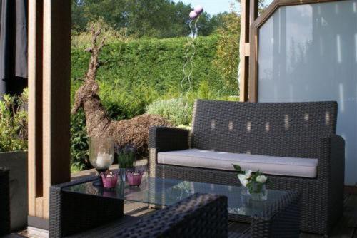 a patio with a glass table and a couch and a camel at Les Jardins d'Ulysse, The Originals Relais in Stella-Plage