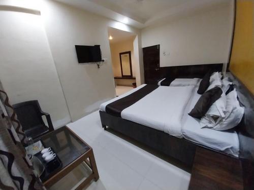 a bedroom with a large bed and a table at Hotel Sachidanand-Walkable distance from Temple in Shirdi