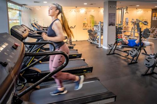 a woman running on a treadmill in a gym at Serhs Natal Grand Hotel & Resort in Natal
