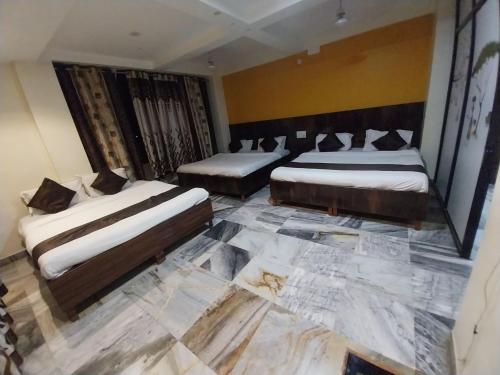 two beds in a room with a marble floor at Hotel Sachidanand-Walkable distance from Temple in Shirdi