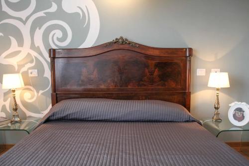 a bed with a wooden headboard in a room with two lamps at Il Fonticolo Room & Breakfast in Modena