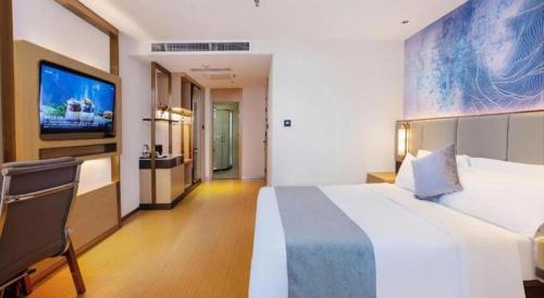 a hotel room with a large bed and a flat screen tv at GreenTree Inn Taiyuan PinGYAng Road Business Hotel in Taiyuan