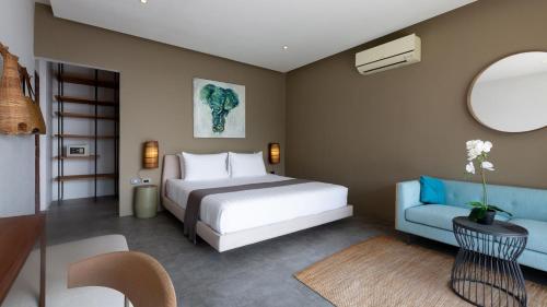 una camera con un letto bianco e un divano blu di Villa Thansamaay by Elite Havens a Laem Sor