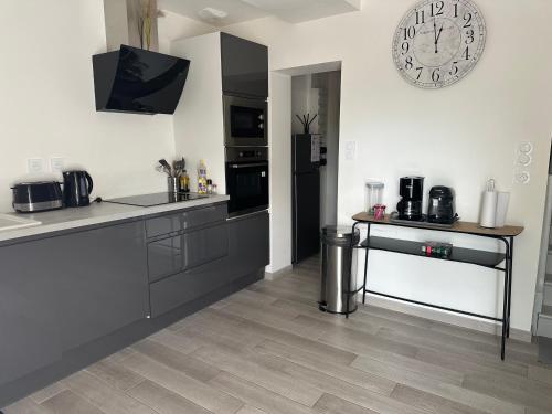 une cuisine avec un comptoir et une horloge au mur dans l'établissement la grande aire, à Saint-Aignan