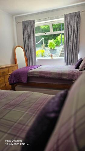 a bedroom with two beds and a window at Jenny's Bay with Hot Tub in Lochgoilhead