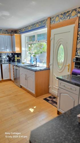 a large kitchen with a sink and a window at Jenny's Bay with Hot Tub in Lochgoilhead