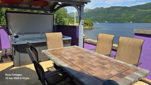 a table and chairs on the back of a boat at Jenny's Bay with Hot Tub in Lochgoilhead