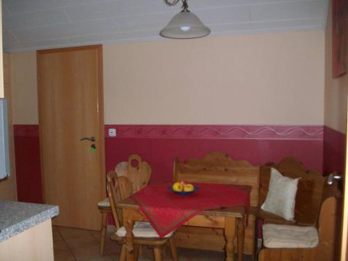 eine Küche mit einem Tisch und Stühlen mit einem roten Tischtuch in der Unterkunft Ferienwohnung Mastiaux in Mirbach