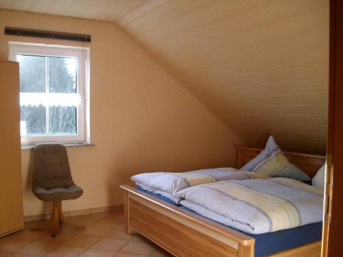 een bed in een kamer met een raam en een stoel bij Ferienwohnung Mastiaux in Mirbach