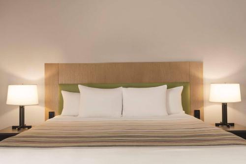 a bedroom with a bed with white pillows and two lamps at Country Inn & Suites by Radisson Raleigh-Durham Airport NC in Morrisville