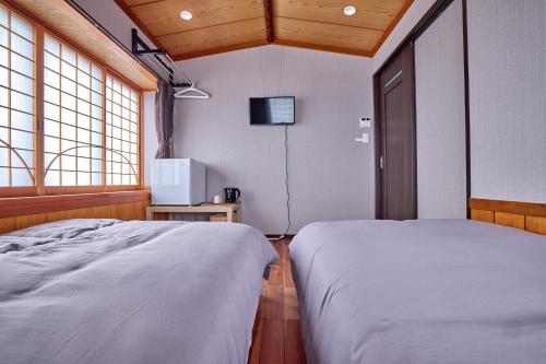 a bedroom with two beds and a tv in it at ホテル海里 in Fujikawaguchiko