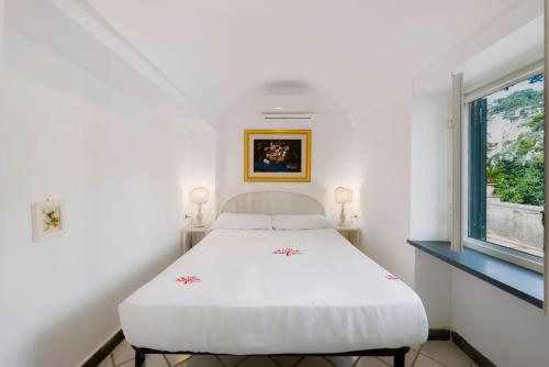 a white bed in a room with a window at La Perla Marina Suite in Capri