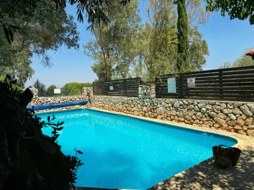 a swimming pool with a stone wall and blue water at THE HOUSE ROSH PINA - 3BRM WITH POOl in Rosh Pinna