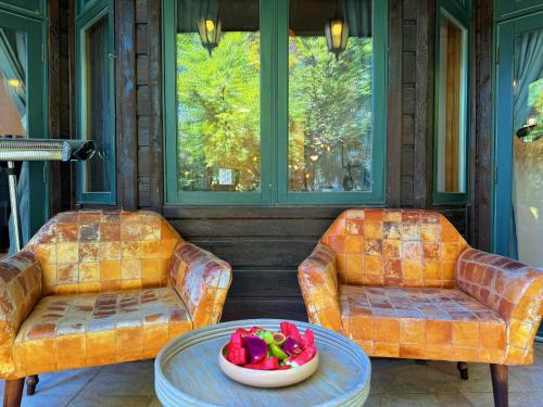 two chairs and a table with a bowl of fruit on a porch at THE HOUSE ROSH PINA - 3BRM WITH POOl in Rosh Pinna