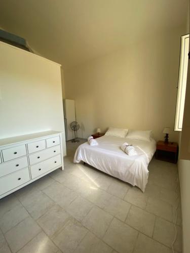 a bedroom with a white bed and a dresser at Old cowshed from the '30 in Santa Maria Coghinas