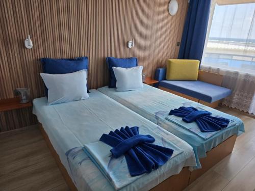 a bedroom with a bed with blue sheets and a chair at Family hotel Delfina in Tyulenovo