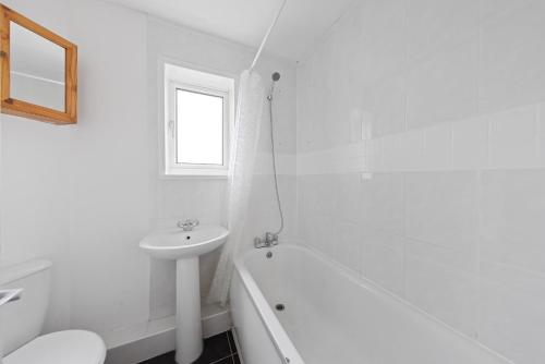 a white bathroom with a sink and a tub and a toilet at 2 Bedroom Modern house in Rainham