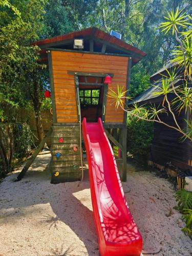 a red slide in front of a play house at הבית בראש פינה - The House in Rosh Pinna