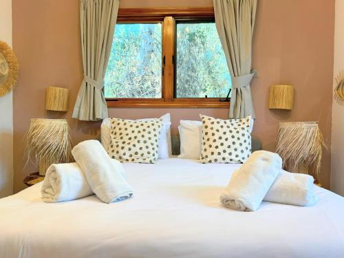 a bedroom with two beds with pillows and a window at הבית בראש פינה - The House in Rosh Pinna
