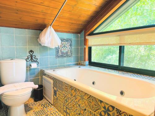 a bathroom with a tub and a toilet and a window at הבית בראש פינה - The House in Rosh Pinna