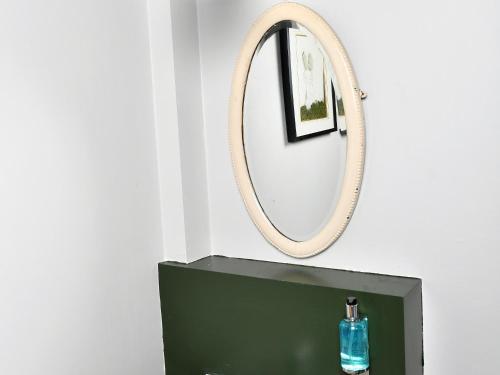 a mirror above a green sink with a bottle on it at YHA Windermere in Troutbeck