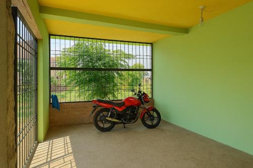 a red motorcycle parked in a room with a window at Green Vista Homestay in Silchar