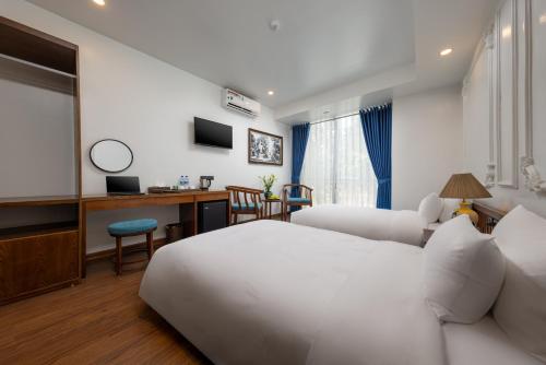 a hotel room with two beds and a desk at Tam Coc Sueno Hotel in Ninh Binh