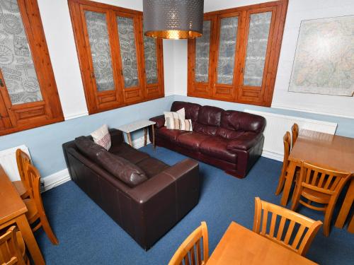 a living room with a leather couch and a table at YHA Windermere in Troutbeck