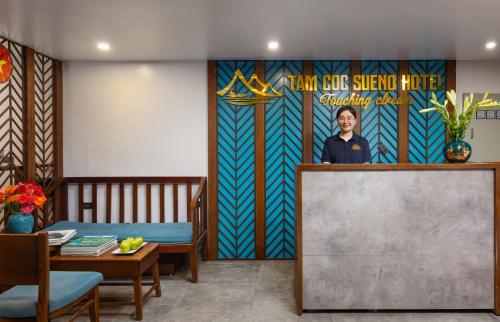 a woman standing behind a podium in a room with a mural at Tam Coc Sueno Hotel in Ninh Binh