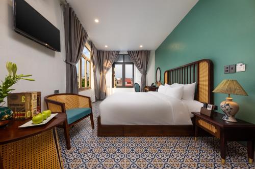 a bedroom with a white bed and a desk and a table at Tam Coc Sueno Hotel in Ninh Binh