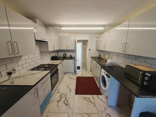 a large kitchen with white cabinets and a washing machine at SnoozeDen Chalvey - Free Parking, Near M4 J6 in Slough