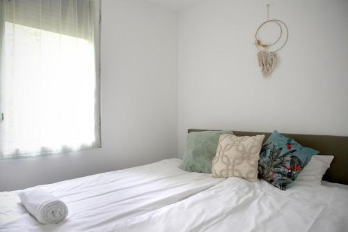 a bed with white sheets and pillows and a window at Casa Libre in Balatonalmádi