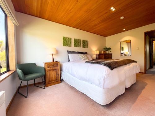 a bedroom with a large bed and a chair at Glenorchy Lake House in Glenorchy